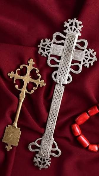Ethiopian Orthodox golden hand cross with intricate lattice metalwork and a shaped handle.